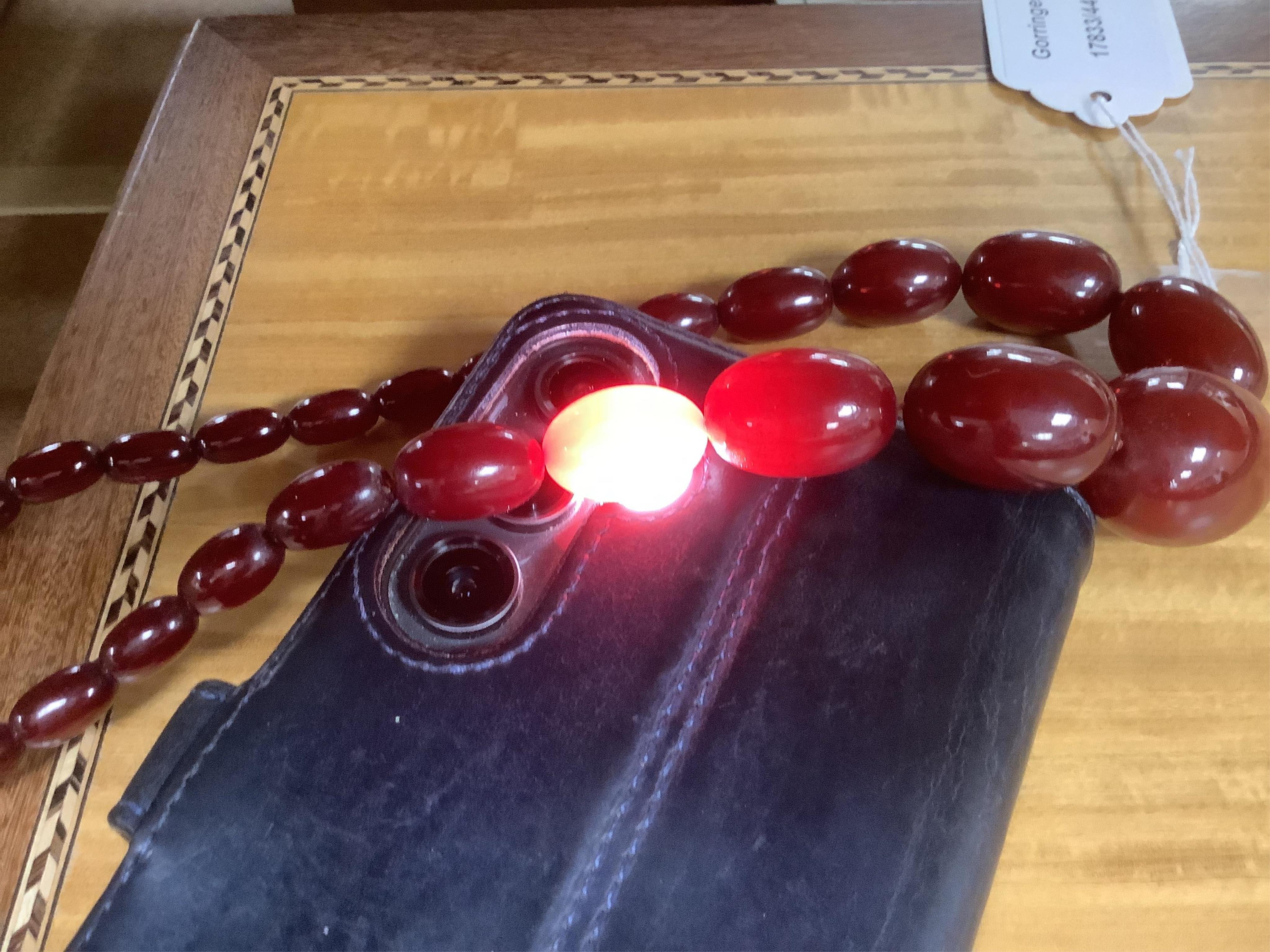 A single strand graduated oval simulated amber bead necklace, 72cm, gross weight 64 grams, together with a simulated cherry amber bracelet.